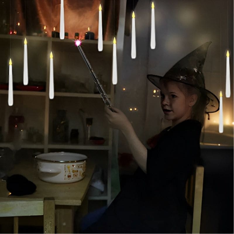 jeu fille qui s'est déguisée en sorcière assis a la table devant son chaudron tient dans sa main une baguette magique qui allume bougie flottante au plafond comme dans Harry Potter