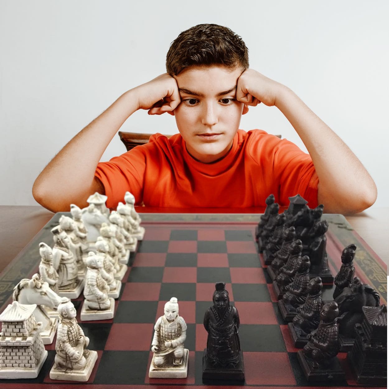 Un adolescent devant un jeu d'échec en ois artisanal il réfléchit et admire son cadeau