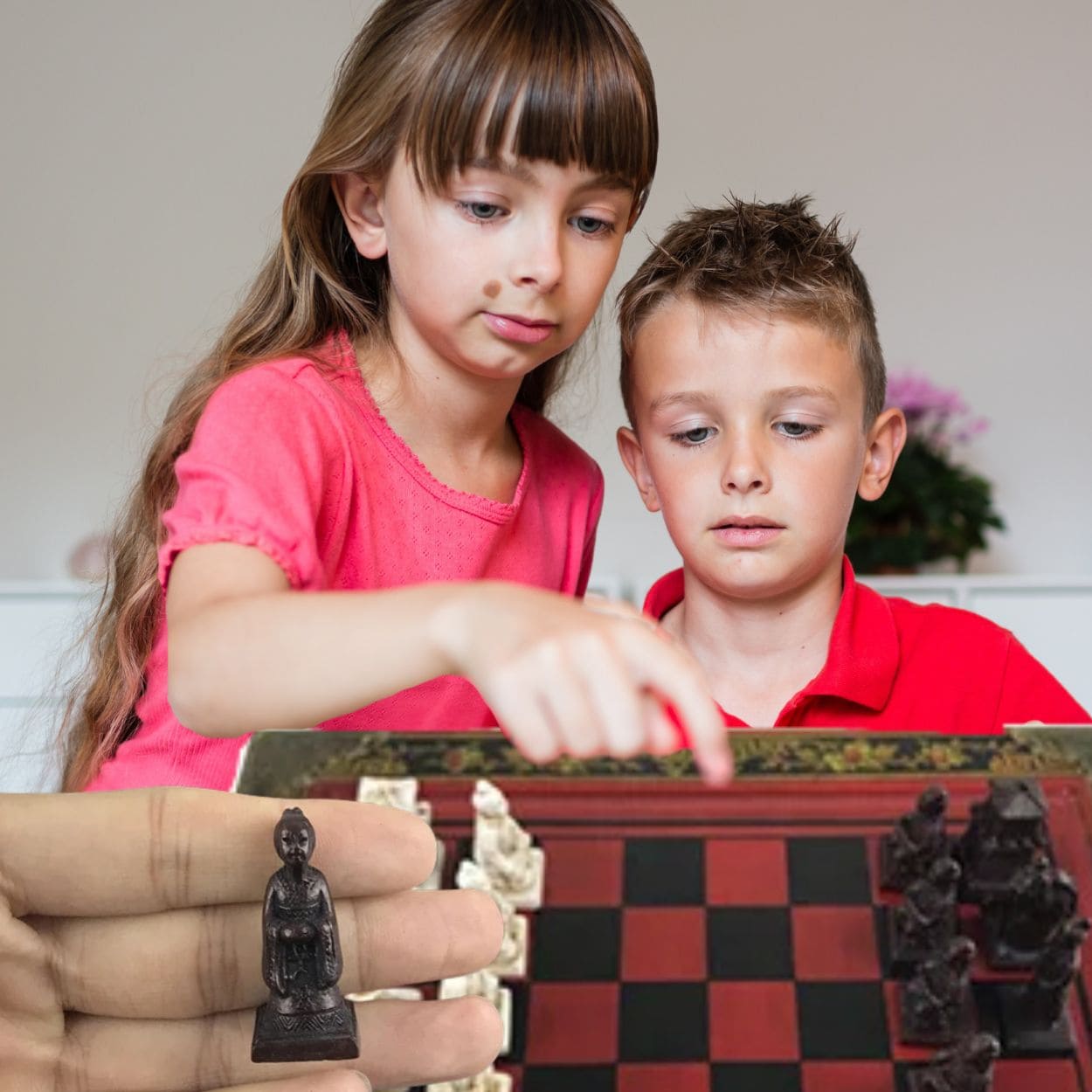 2 enfants curieux d'apprendre à jouer au jeu d'échec en bois artisanal laissé sur la table du salon en déco