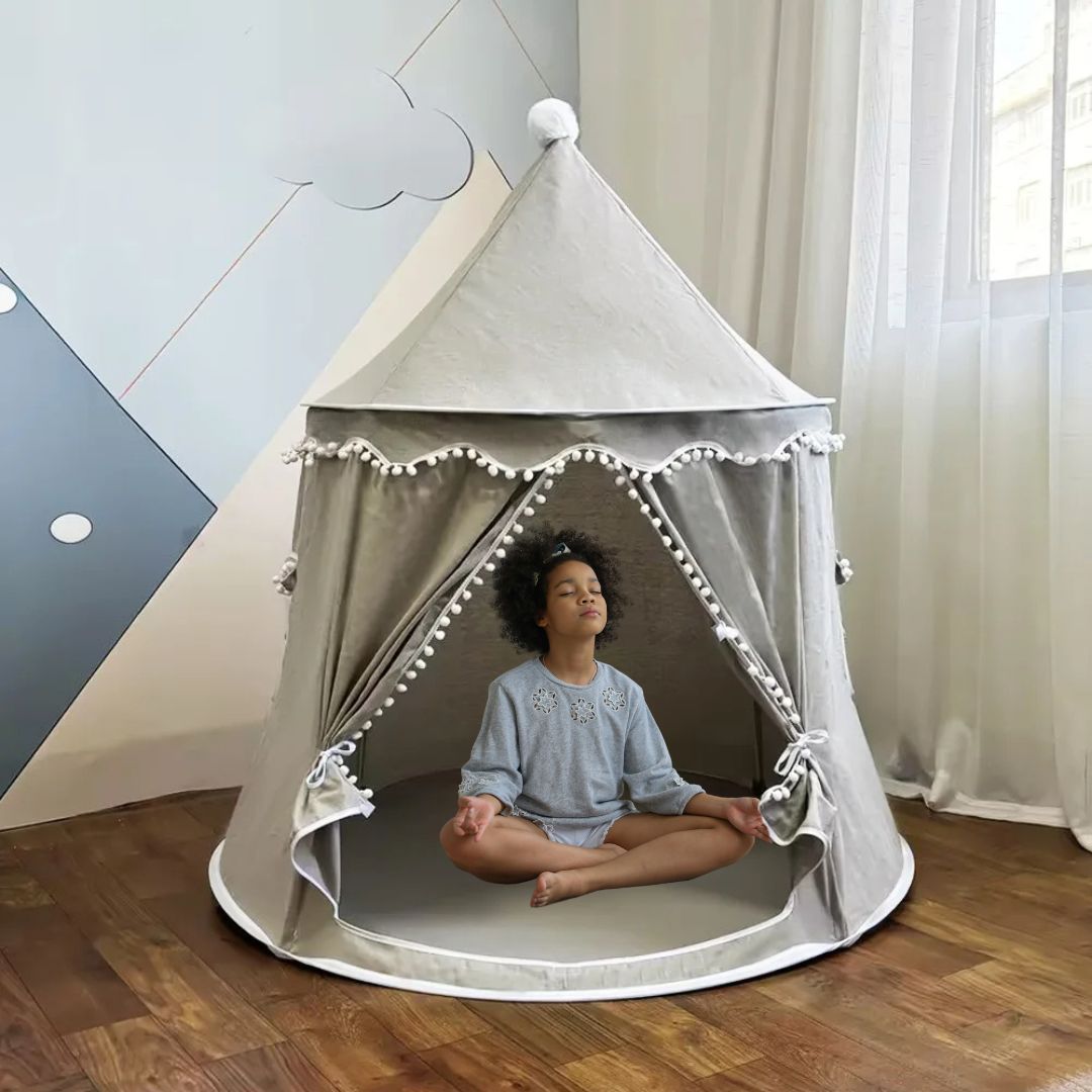 une belle jeune fille médite les jambes croisée très à son aise dans son grand tipt enfant gris dans un coin de chambre