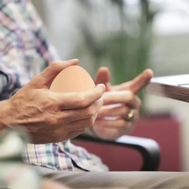 une personne fais des exercice de motricité avec cette balle anti stress en forme d oeuf