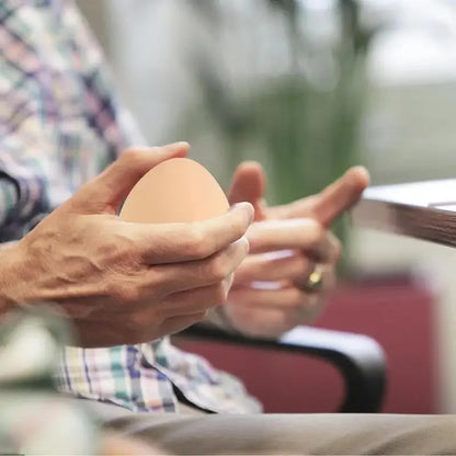 une personne fais des exercice de motricité avec cette balle anti stress en forme d oeuf
