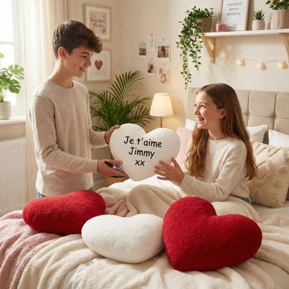 un garçon donne un cœur st valentin blanc en coussin moelleux sur lequel il lui a écrit un message d amour. cadeau de st-Valentin réussi.