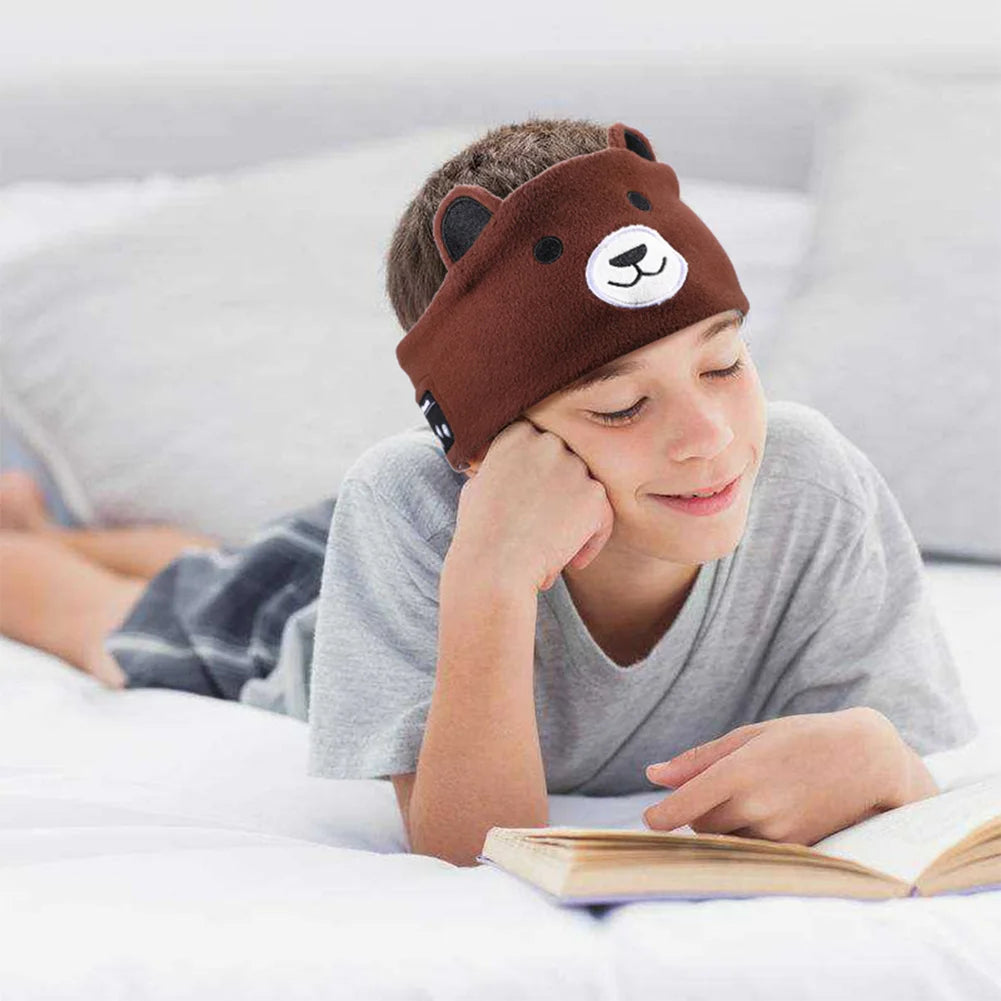 le garçon lit en écoutant de la musique grâce à son casque audio bandeau ours brun
