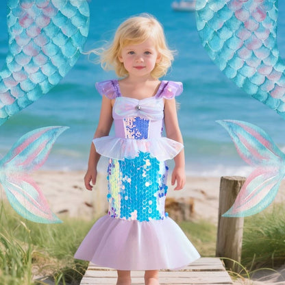 Belle petite fille sur le quai de bois porte son déguisement sirene aux écailles argentées briillant au soleil de toute beauté