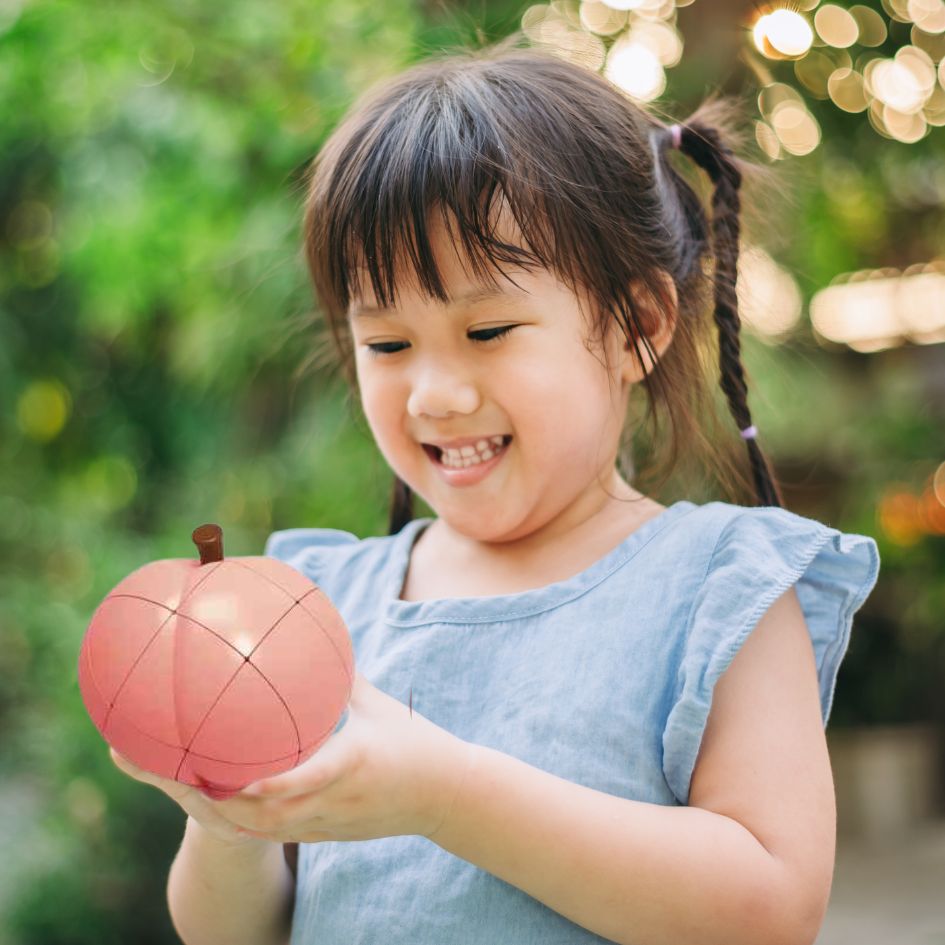 une jeune fille de 6 ans tient une grosse pèche en Puzzle 3d rubiks cube 