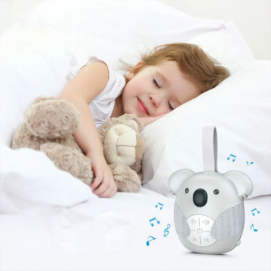 une fillette dort paisiblement dans son lit douillet accompagnée de sa Veilleuse bruit blanc musicale portable Koala grise