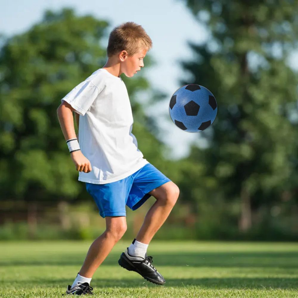 le garçon pratique son jeu de jambes pour le foot avec un ballon en mousse doux et sans douleur