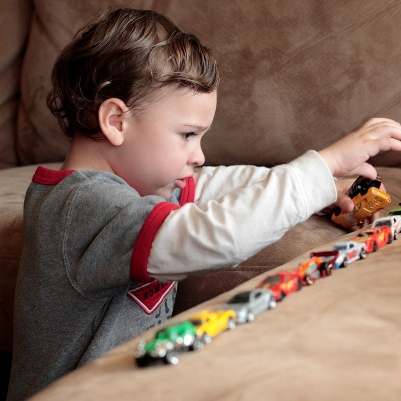 un bambin de 3 ans joue avec ses 24 oitures jouets de son nouveau calendrier de l'avent enfant 2024
