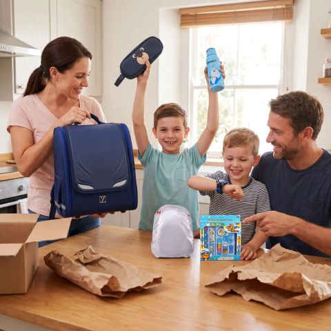 une famille heureuse de déballer le cartable enfant avec tyous ses 5 cadeau offerts gratuitement