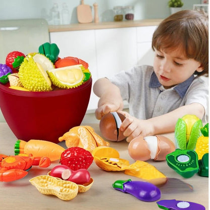 garçon concentré à couper un kiwi en plastique a velcro pour faire semblant en jouant à la cuisine enfant