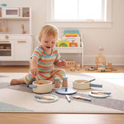 un bébé de 2 ans brasse la soupe avec ses ustensiles de sa dinette en bois assiette, ustensiles en bois