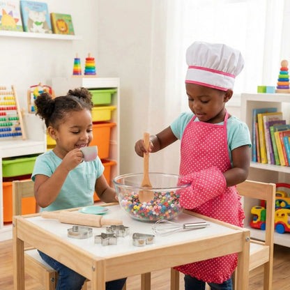 2 fillettes mignonnes jouent à faire semblant de cuisiner et de prendre le thé dans la dinette enfant avec un TABLIER CUISINE ENFANT rose