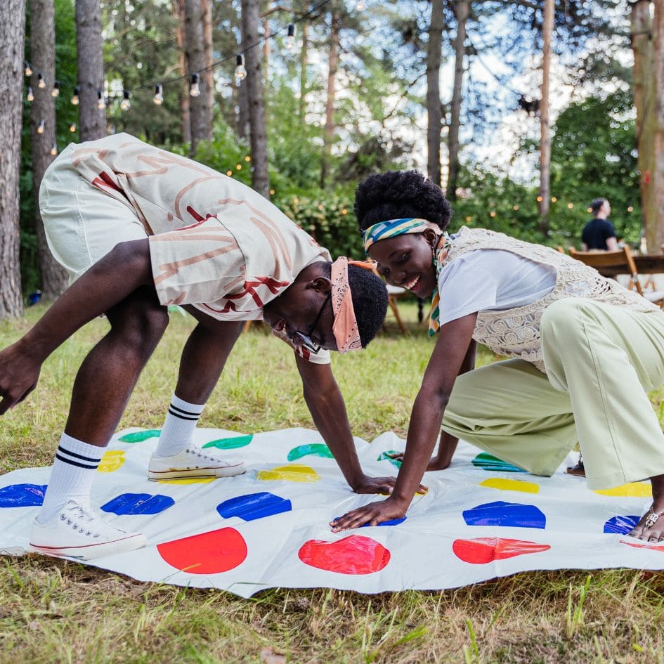 deux adultes homme et femme jouent au jeu de société Twister lors d'un pique Nique au parc en pleine nature romantique et très drôle propice aux rapprochements