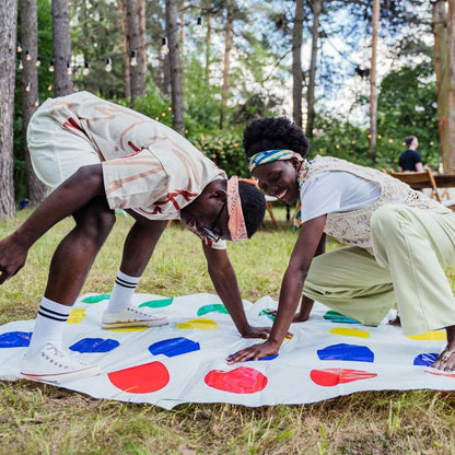 deux adultes homme et femme jouent au jeu de société Twister lors d'un pique Nique au parc en pleine nature romantique et très drôle propice aux rapprochements