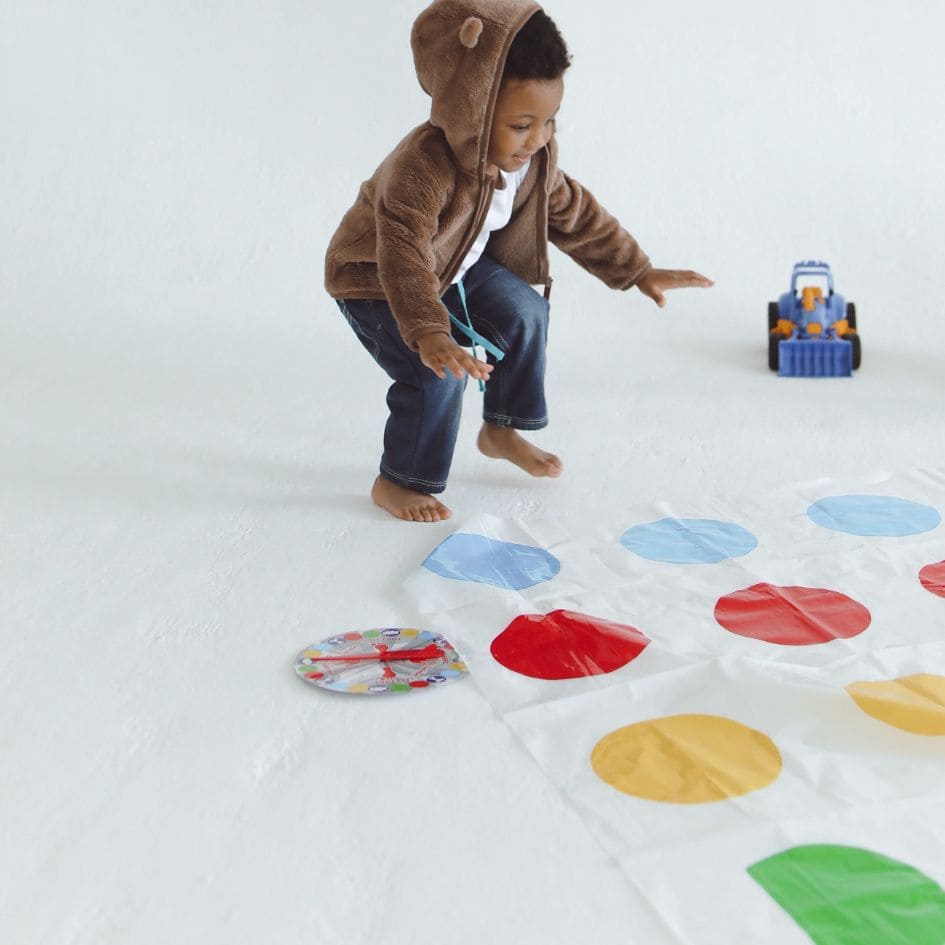 un bambin de 3 ans joue au jeu de société Twister