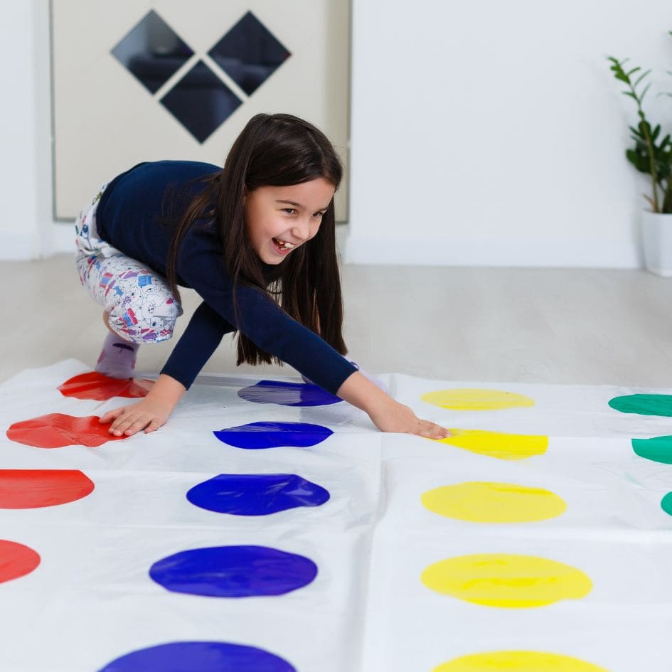 une fillette rit de bon coeur en jouant au jeu de société Twister