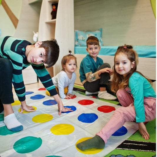 des enfants s'amusent et rient très fort en jouant aun jeu de société Twister dans la salle de jeu lors d'une fête d'enfants