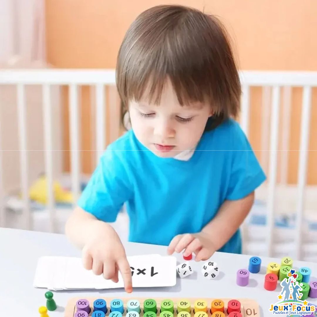 un petit garçon joue au jeu de tables de multiplication en bois avec jeton arc-en-ciel