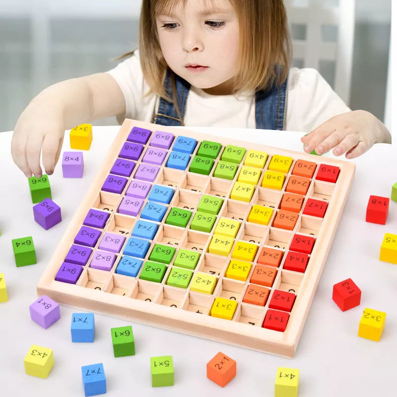 une enfant joue seule avec son jeux de tables de multiplication rempli de blocs de bois colorés