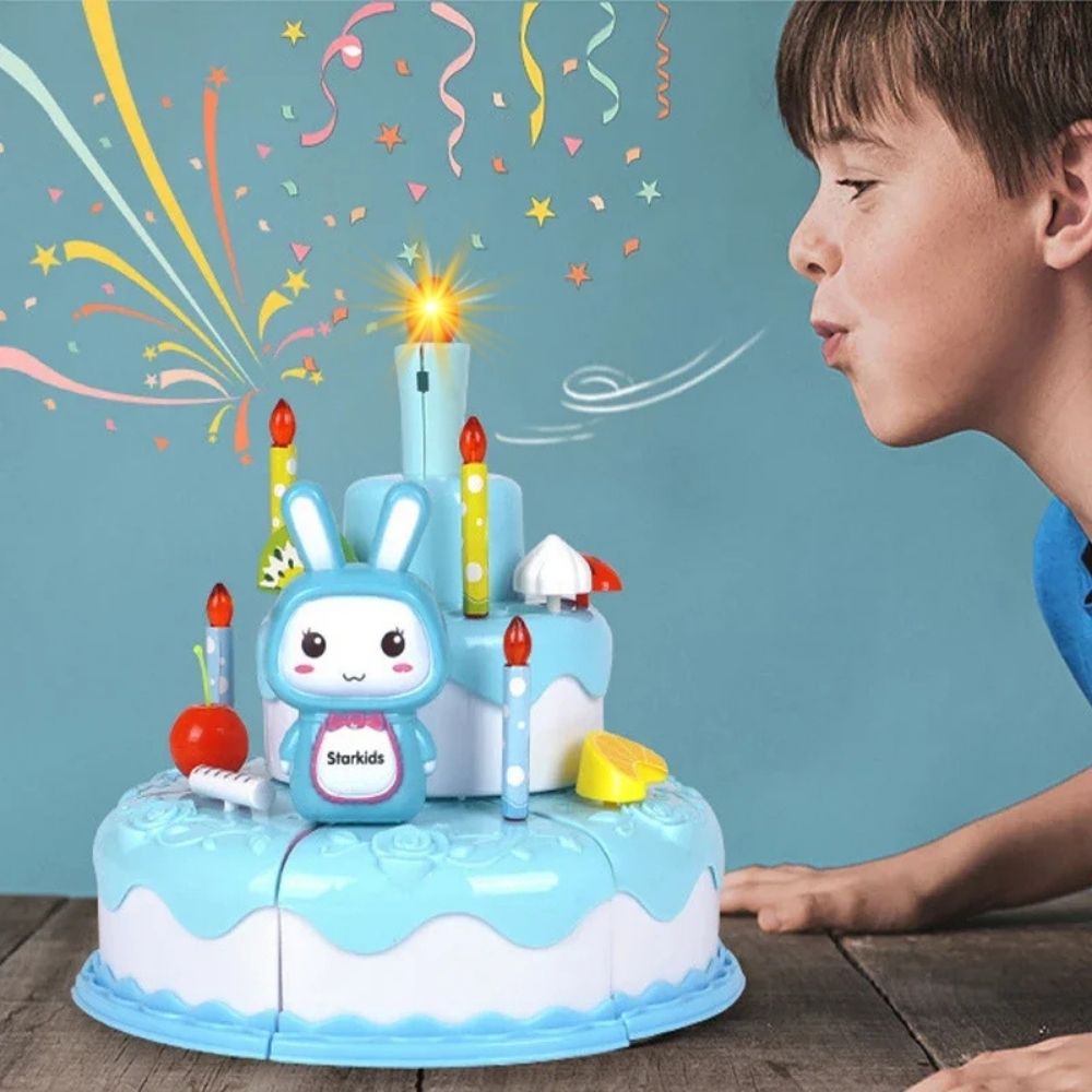 un gamin souffle sur la bougie lumineuse et musicale du gâteau d'anniversaire bleu de ses jouet pour cuisine enfant