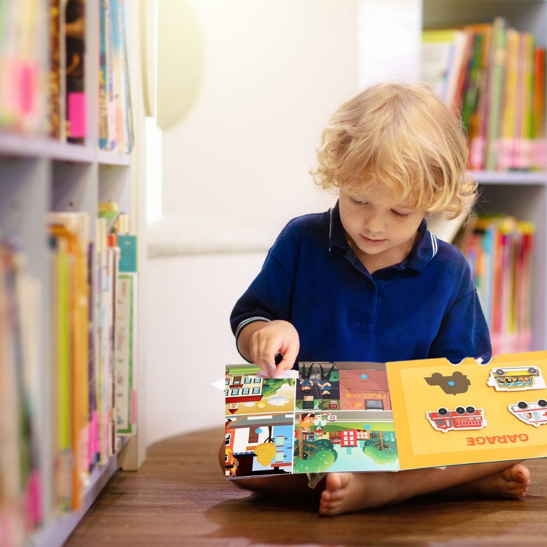le garçon assis dans la bibliothèque avec ses livres pour enfant busy book