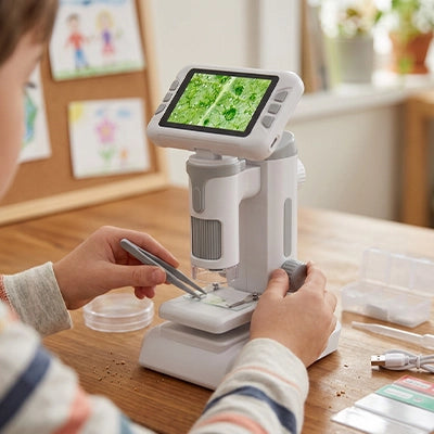 un enfant concentré dépose minutieusement un insecte sur la lamelle de son microscope enfant