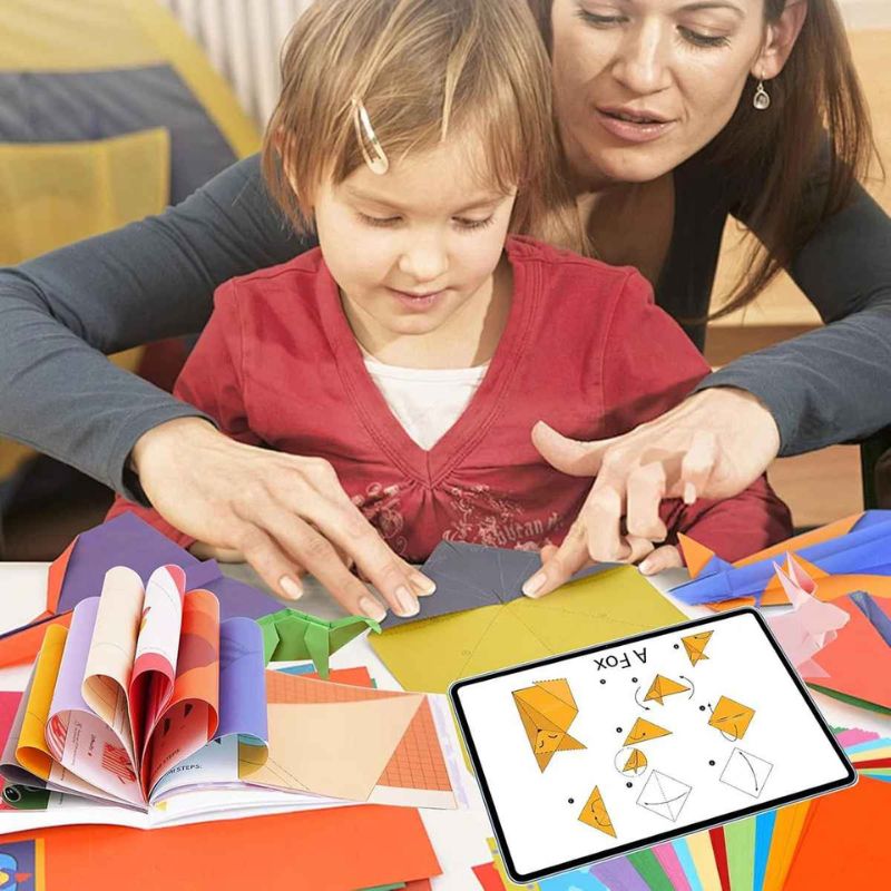 une mère passe du bon temps avec sa fille en famille avec le papier pour origami