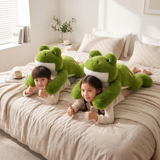 2 enfants couchés sur le lit de leur parent avec une peluche anti stress Lestée modèle grenouille géante