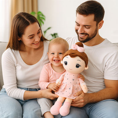 Une fillette très heureuse de recevoir une belle poupée fille rose en tissus coussiné confortable et rassurante.