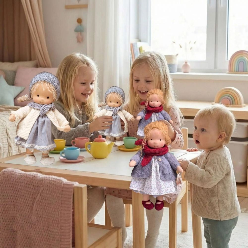 les jumelles jouent avec leur poupee de chiffon blonde avec le service de thé