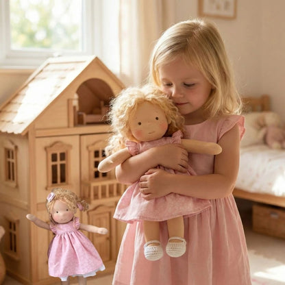 une belle petite fille câline sa poupee de chiffon aux cheveux blonds comme elle