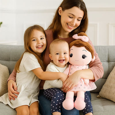 Une maman tient dans ses bras ses 2 filles et une belle poupée fille à câliner