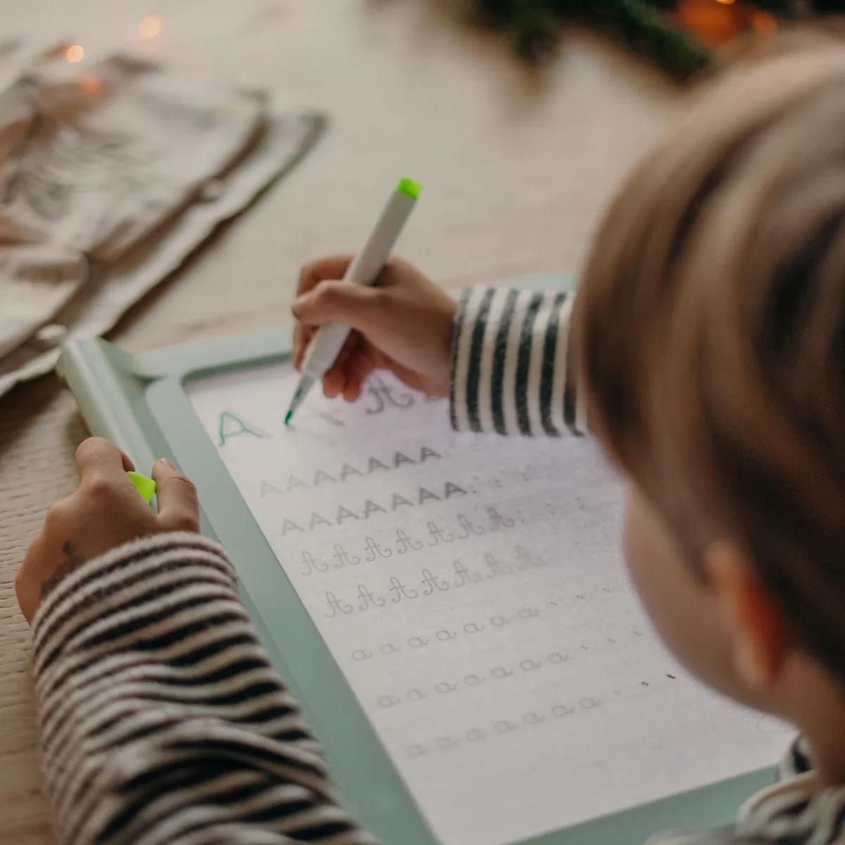 une enfant de 5 ans pratique sa calligraphe sur sa tablette lumineuse à dessin et à mille autres choses