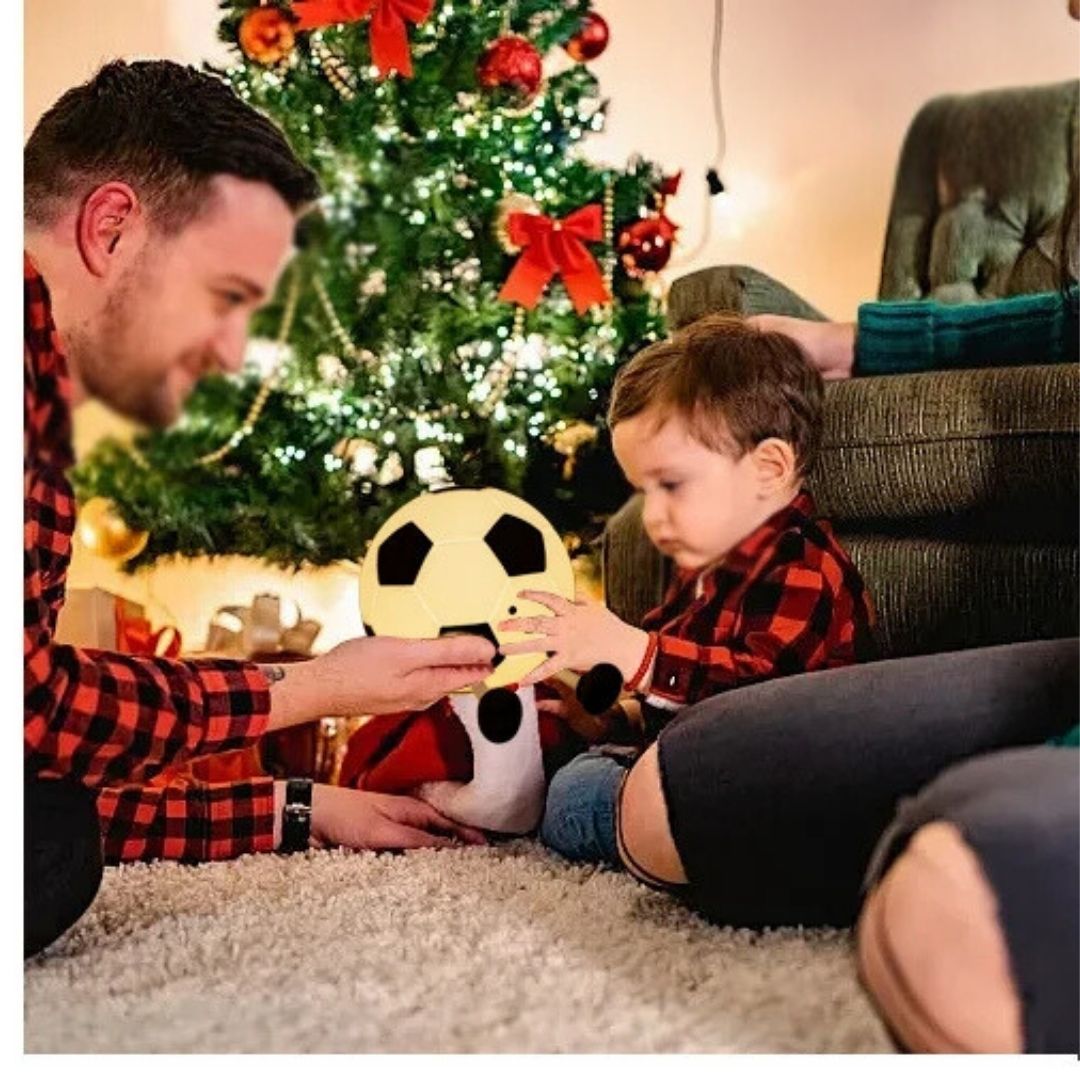 un père roule a veilleuse bébé ballon de foot avec son bambin de 18 mois le soir de Noël