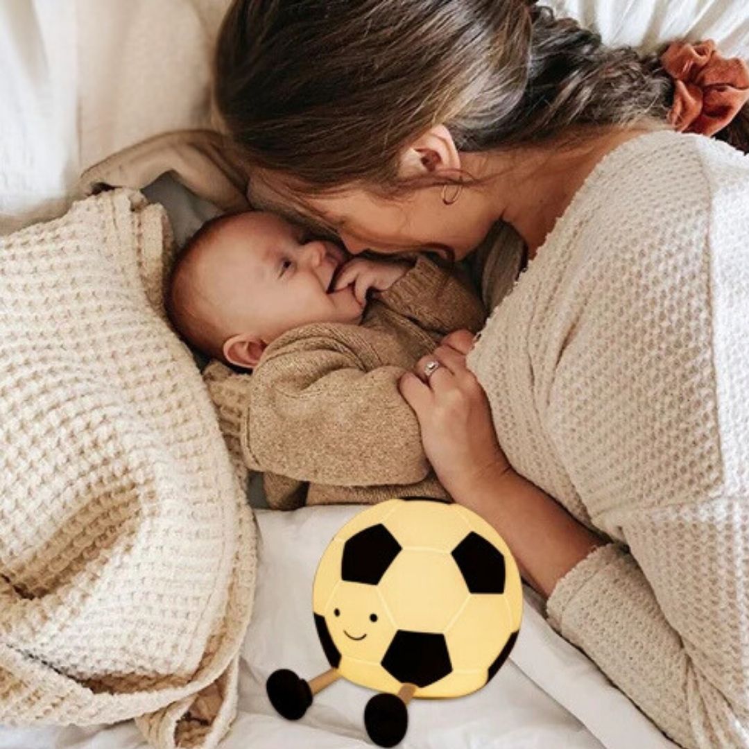 une mère caline son bébé à la lueur de la veilleuse bébé en forme de ballon foot Monsieur Foot